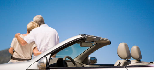 pareja mayor sentados en el capó del coche