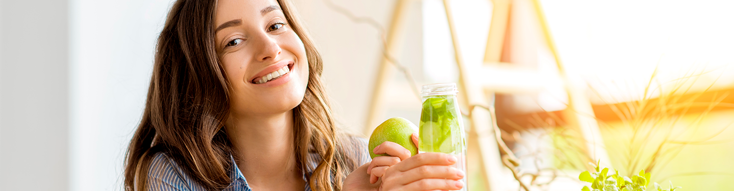 Mujer bebiendo una bebida detox con limón y manzana