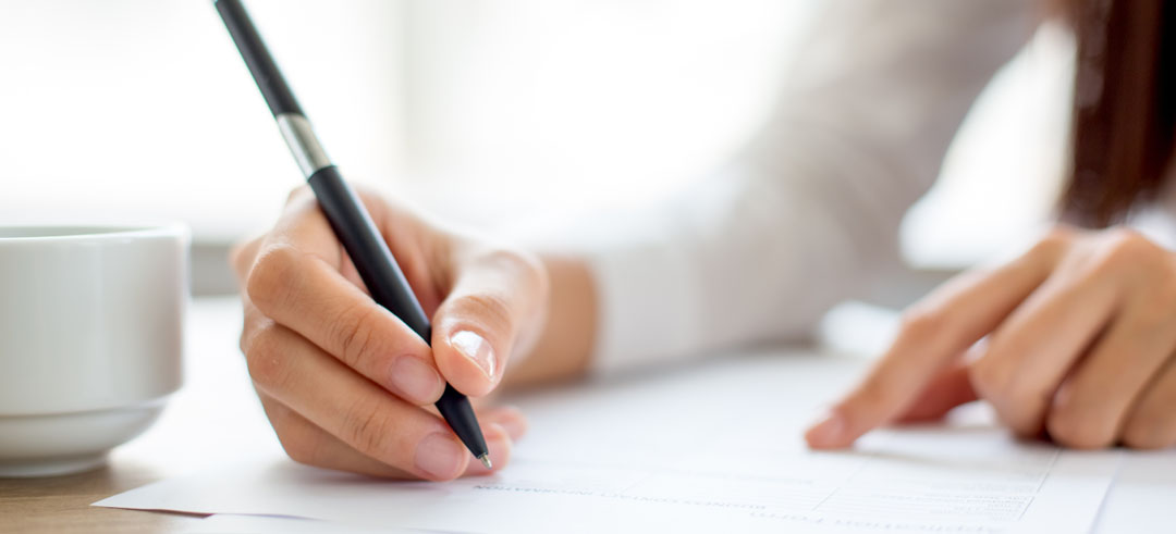 Persona firmando un documento sobre una mesa
