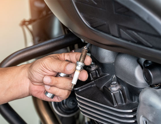 Persona limpiando la bujía de una moto en un taller